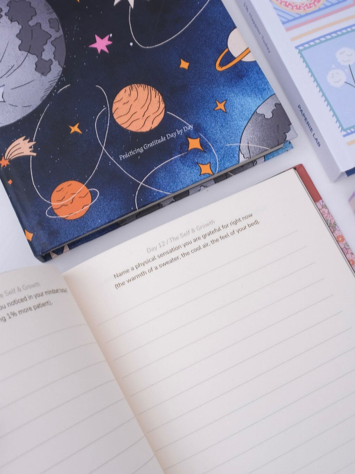 21 Cool Gifts for Adults: Practical Picks for 2026 21 Open gratitude journal and space-themed notebook resting on a white surface.