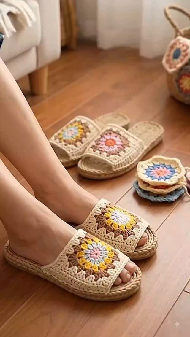 Beige crochet slide slippers with colorful floral patterns worn on a wooden floor.