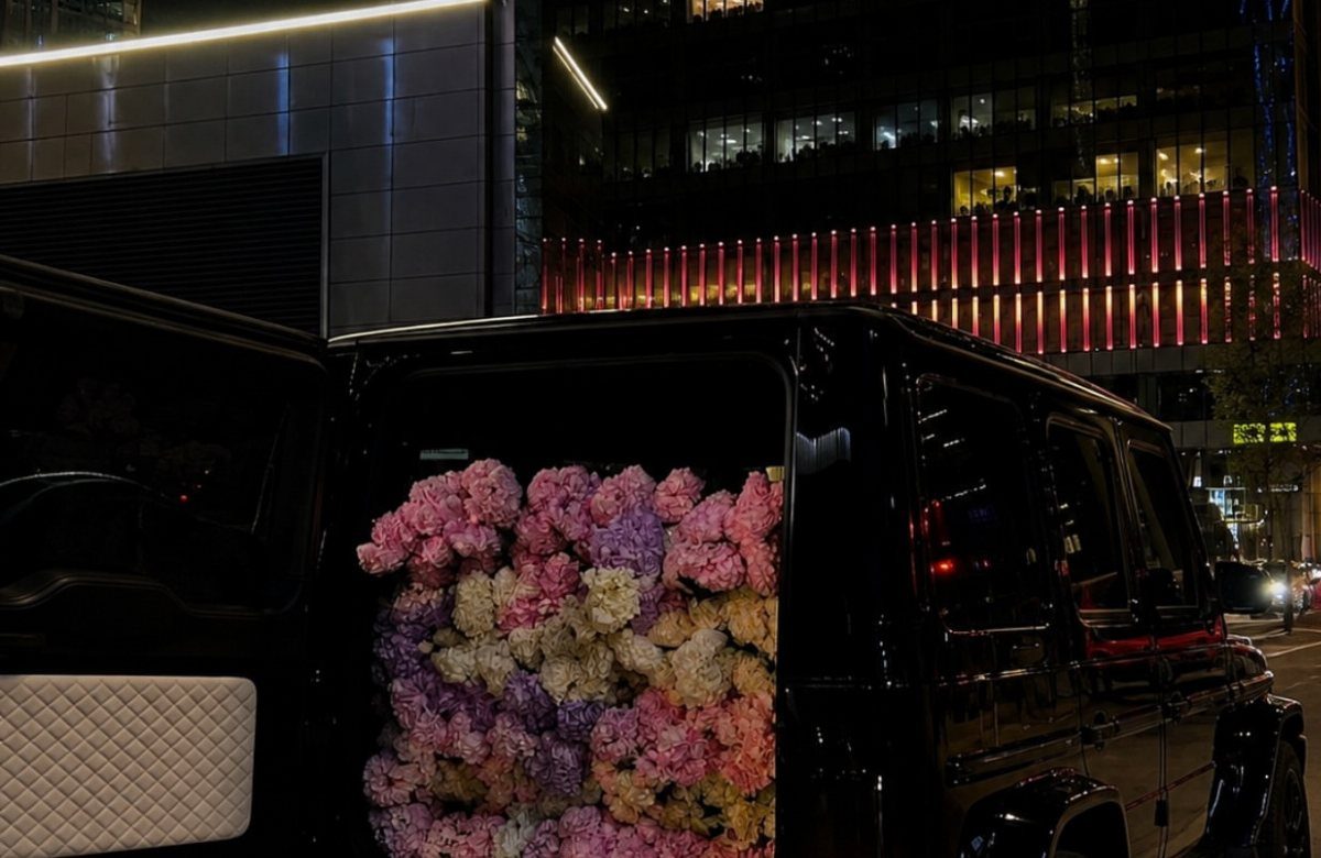 Large bouquet of pink and purple flowers filling the trunk of a black SUV