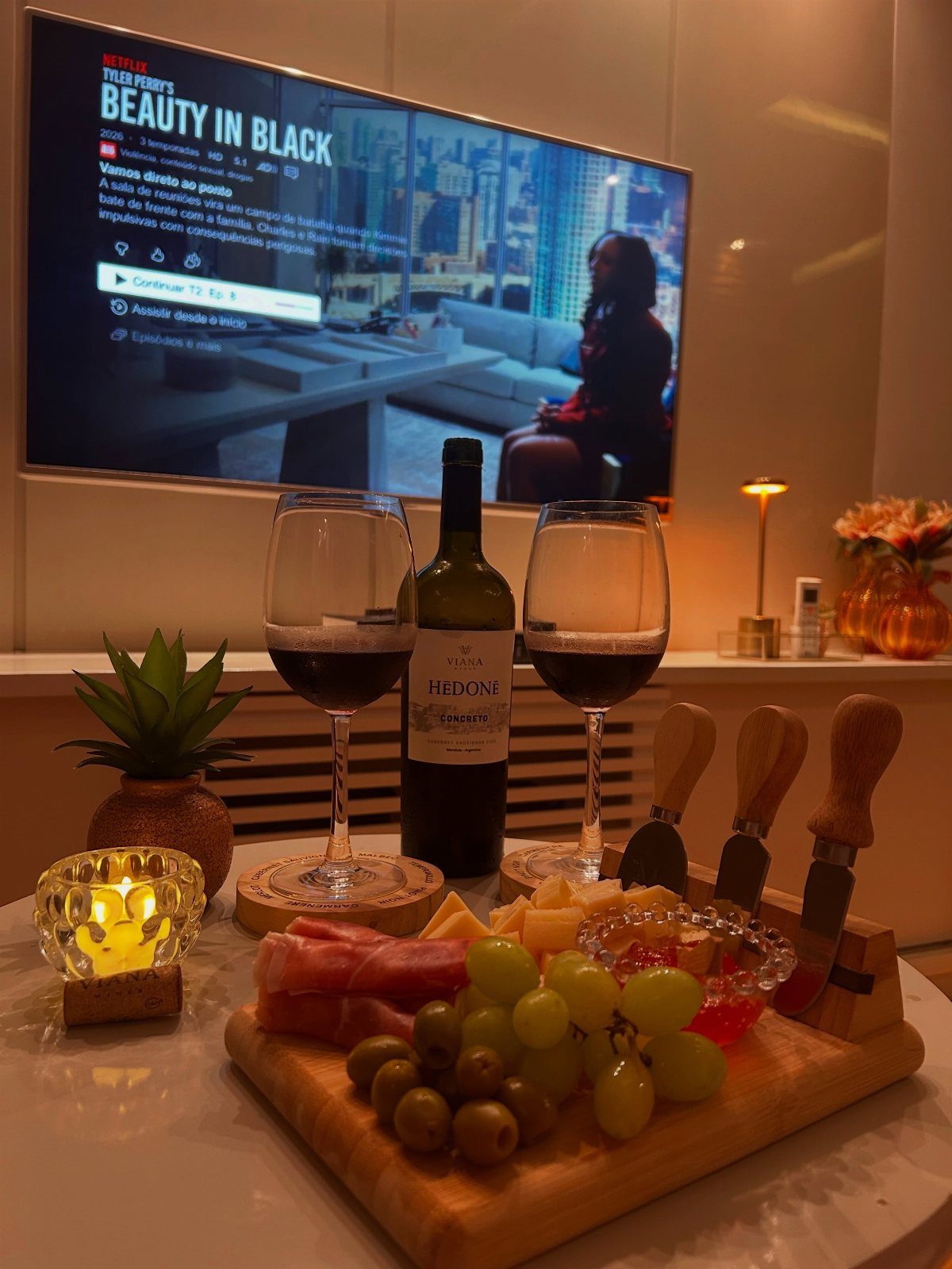 Two glasses of red wine and a charcuterie board on a white table.