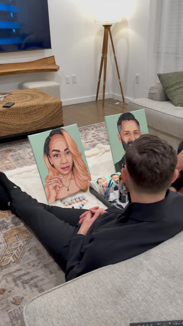 Man looking at two custom painted portraits on a living room rug.