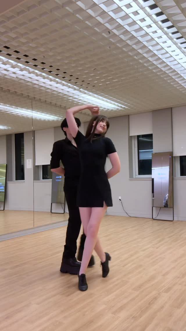 Couple in black attire dancing together in a bright mirrored dance studio