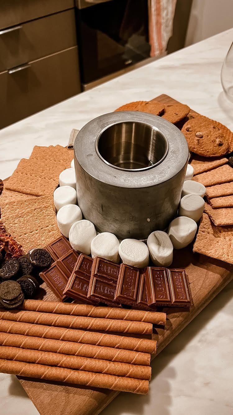 S'mores kit with marshmallows, chocolate, and crackers arranged around a metal heating pot.