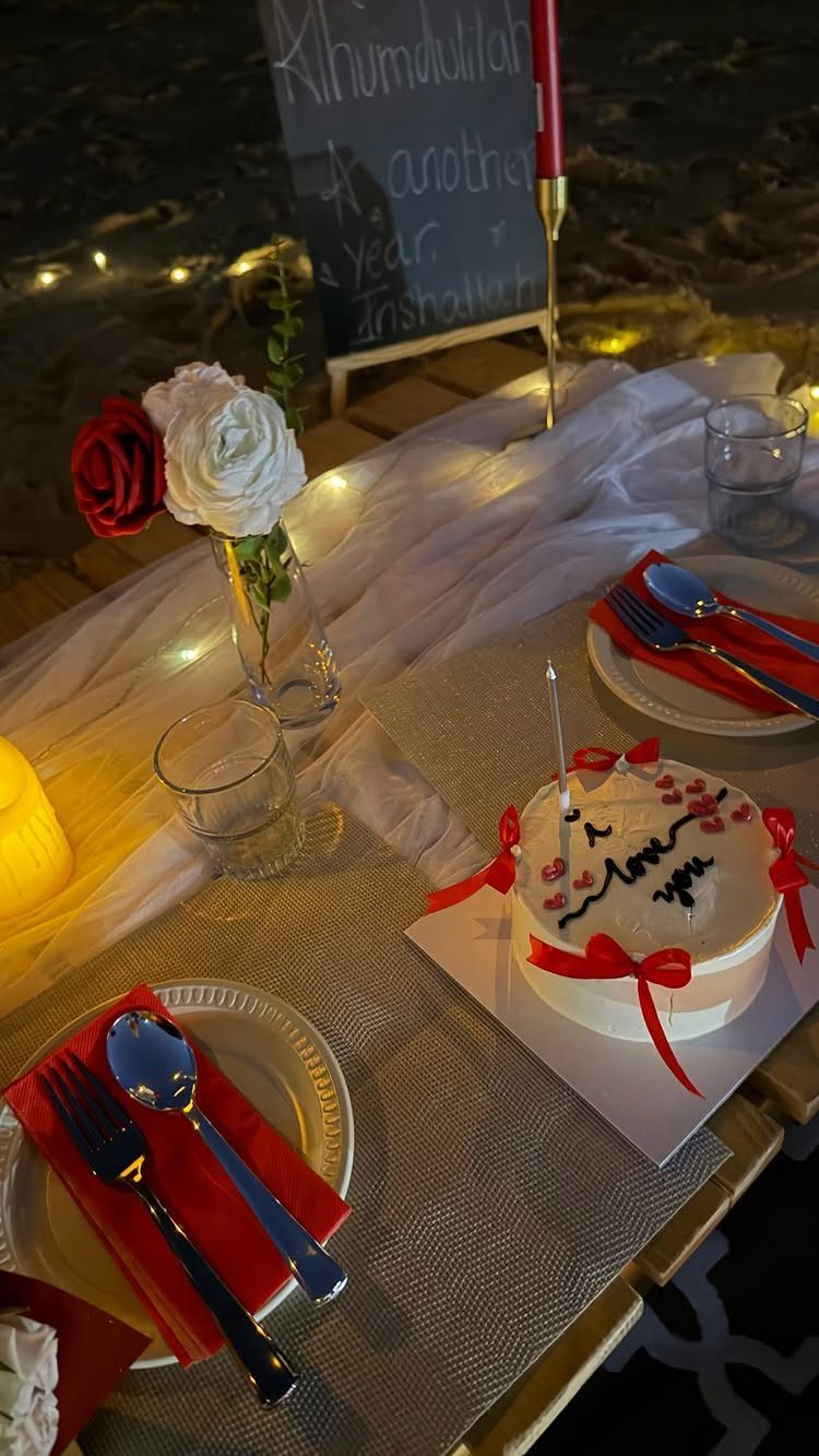Romantic table setting with a white heart cake, red roses, and dinnerware.