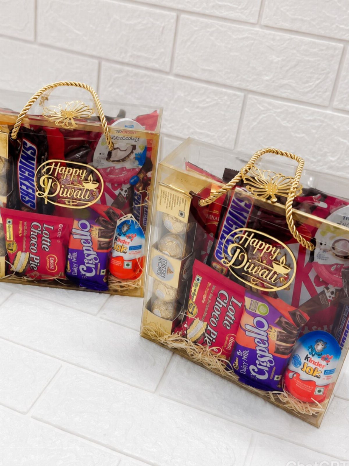 Diwali Gift Hampers: 8 Ideas for Sweets, Dry Fruit & More 7 Two acrylic Diwali gift hampers filled with assorted chocolates and sweets with gold accents.