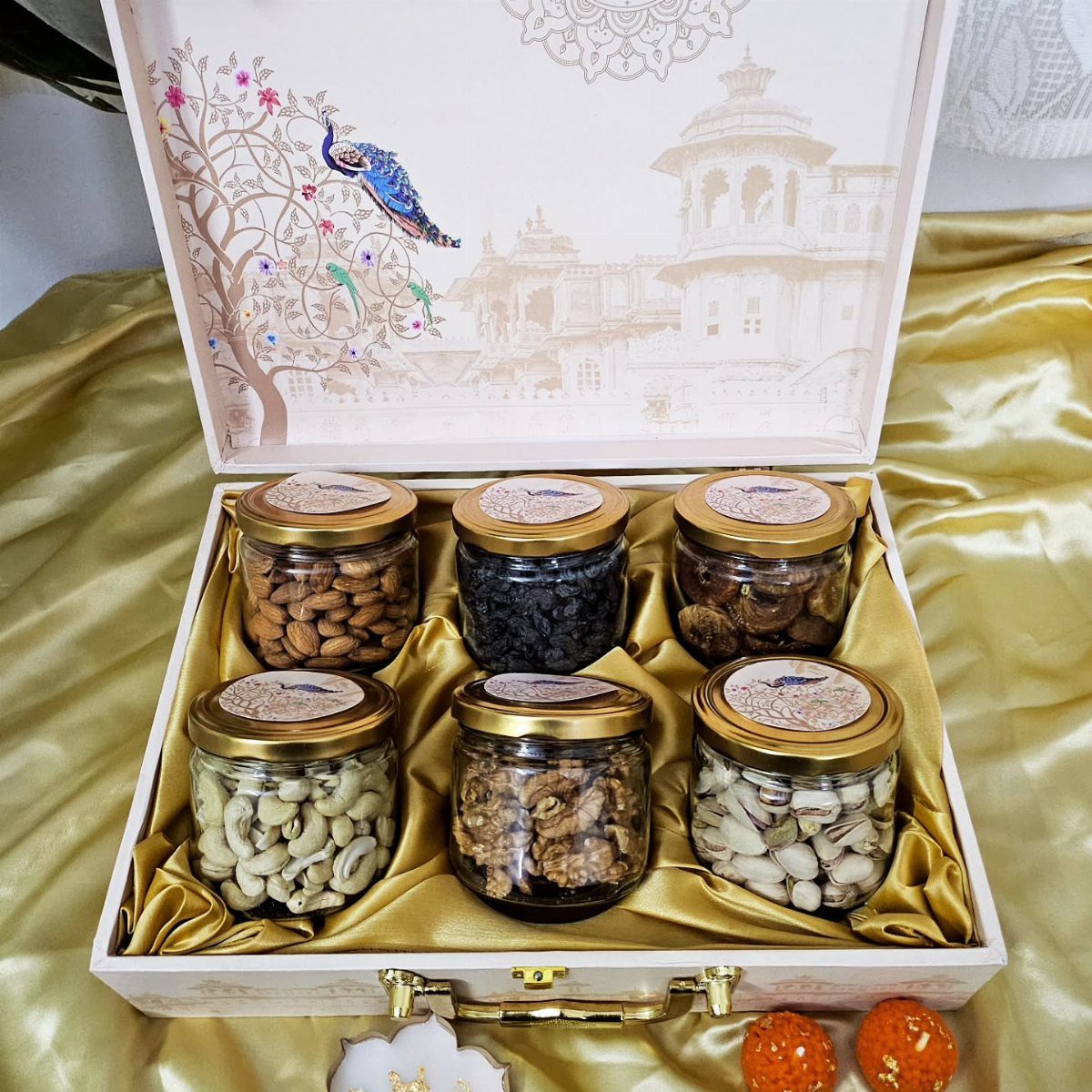 Diwali Gift Hampers: 8 Ideas for Sweets, Dry Fruit & More 2 Six jars of premium dry fruits in a decorative white gift box with gold lining.