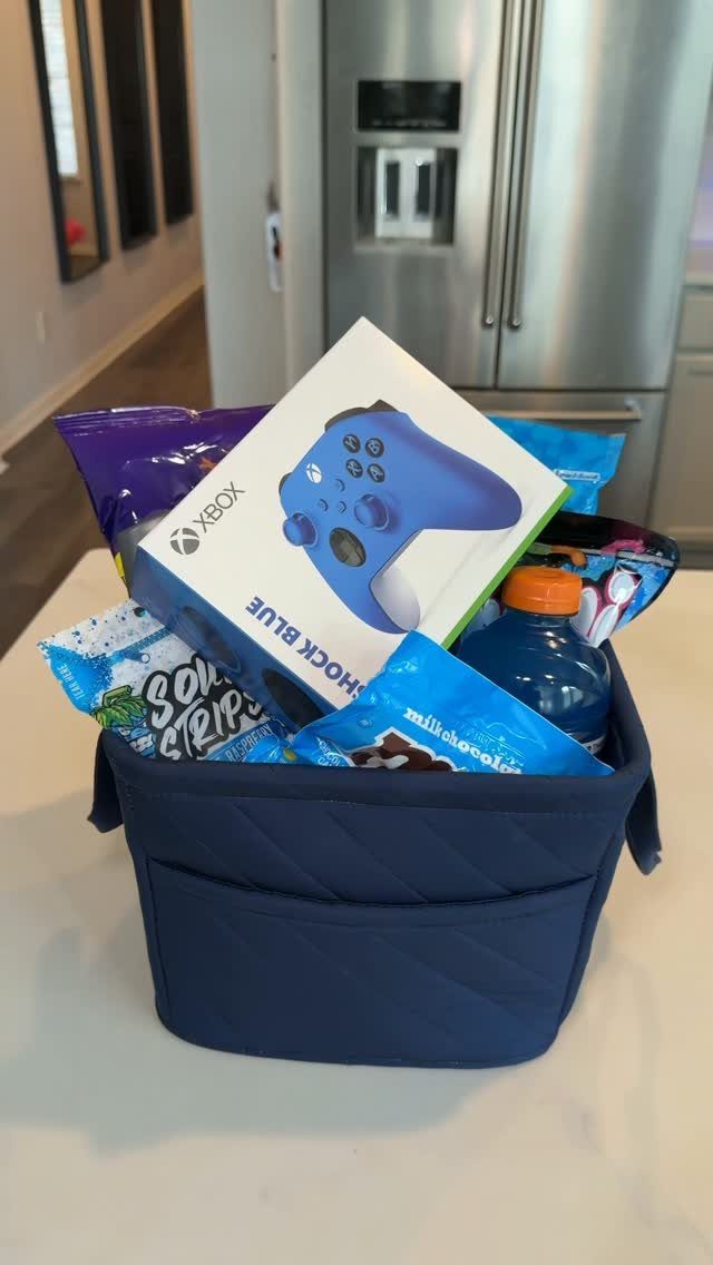 Blue quilted gift basket containing an Xbox controller, snacks, and a blue drink.