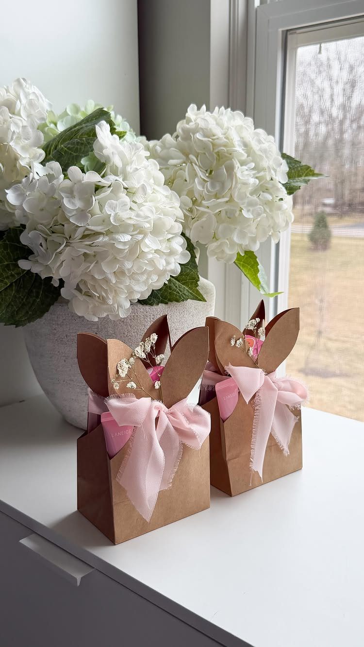 Bunny shaped brown paper gift boxes with pink ribbons and white hydrangeas.