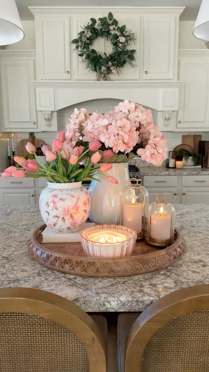 Pink tulips and hydrangeas in white vases with candles on a marble counter