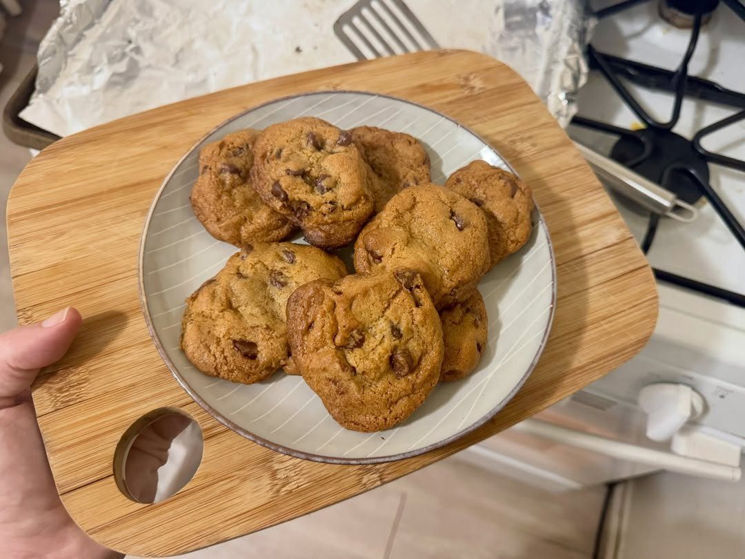 13 Easy Gifts for Neighbors You Can Make or Bake 9 Chocolate chip cookies on a grey plate resting on a wooden cutting board.