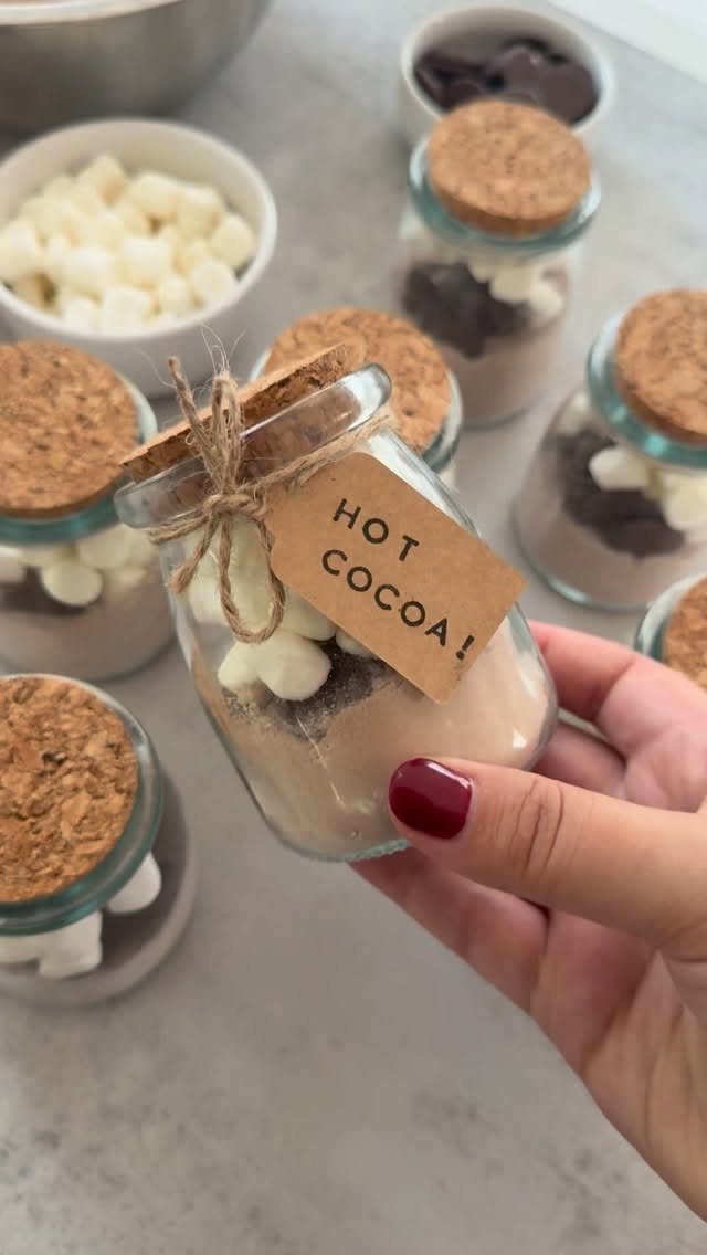 13 Easy Gifts for Neighbors You Can Make or Bake 2 Small glass jar filled with hot cocoa mix and marshmallows held by hand.