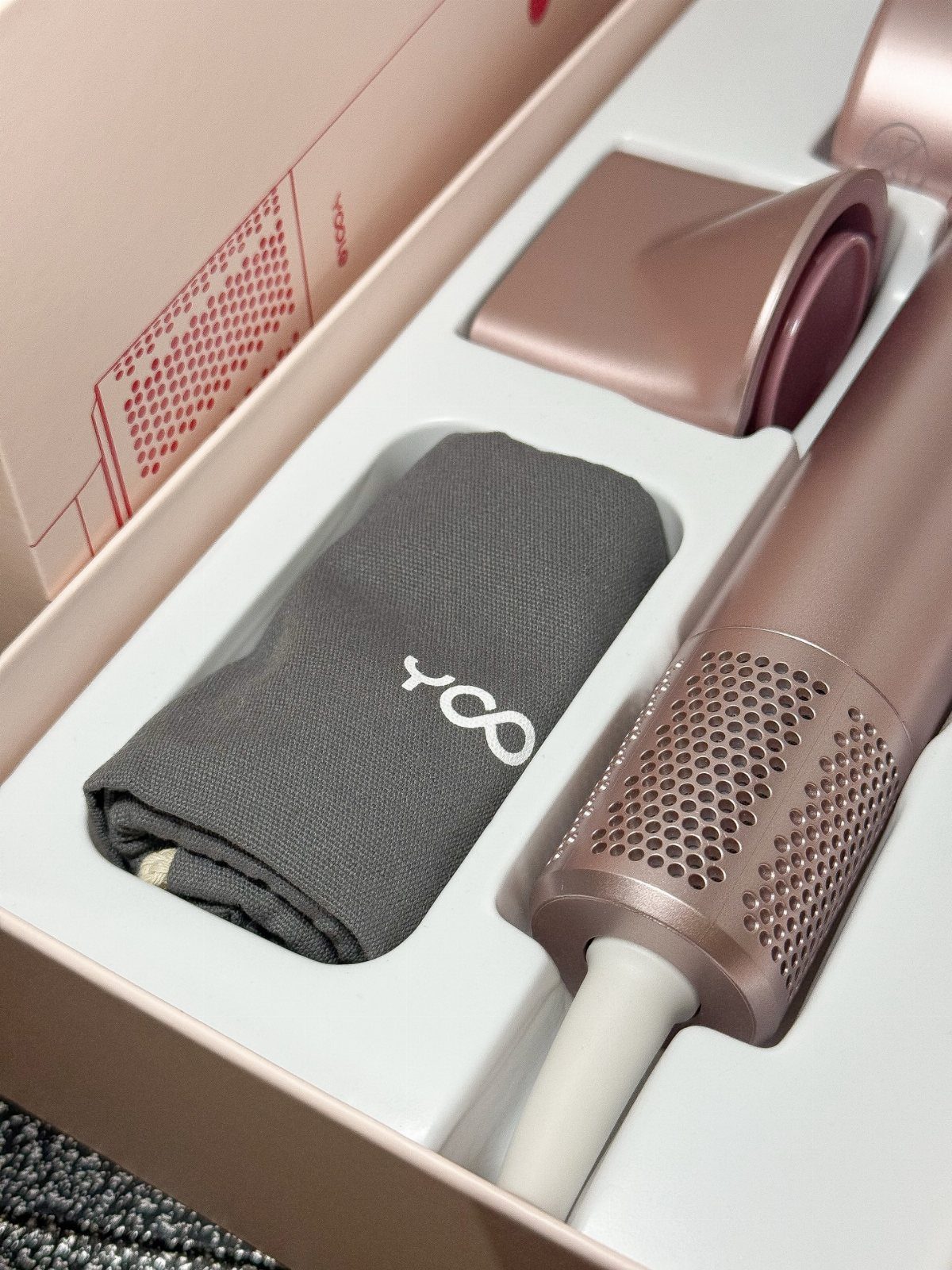Rose gold hair curling iron and grey pouch in a pink gift box