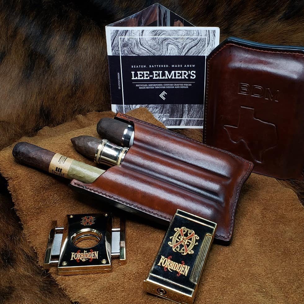 7 Father in Law Gift Ideas He'll Actually Use 5 Leather cigar case with cigars, gold cutter, and lighter on brown suede background.