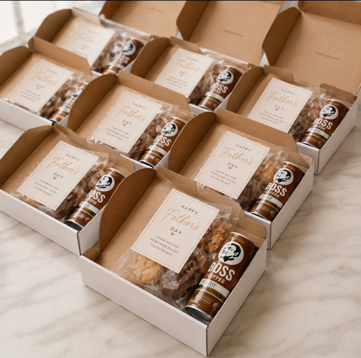 7 Father in Law Gift Ideas He'll Actually Use 2 Father's Day gift boxes containing coffee cans, cookies, and greeting cards on marble.
