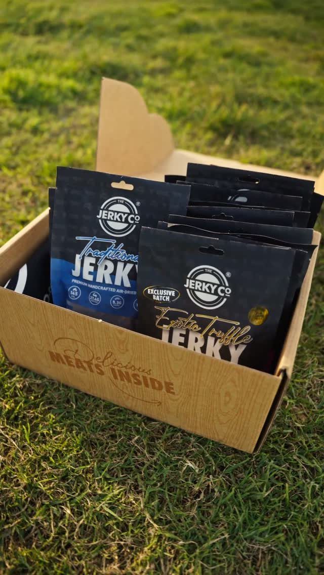 8 Fathers Day Gift Basket Ideas for Every Kind of Dad 1 Cardboard gift box filled with black jerky pouches resting on green grass.