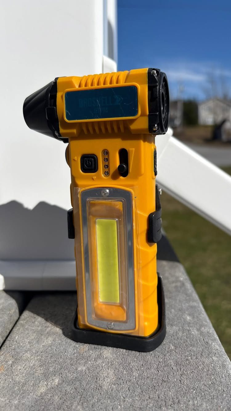 Yellow handheld LED flashlight standing on a grey concrete surface outdoors.