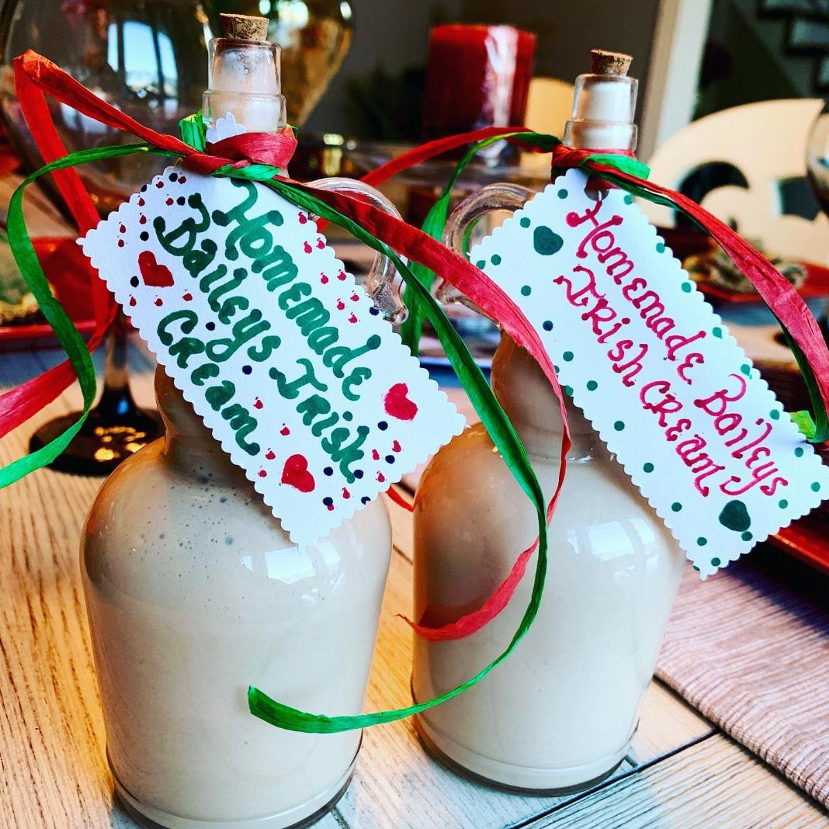 Two bottles of homemade Baileys Irish cream with festive ribbons and handwritten tags.