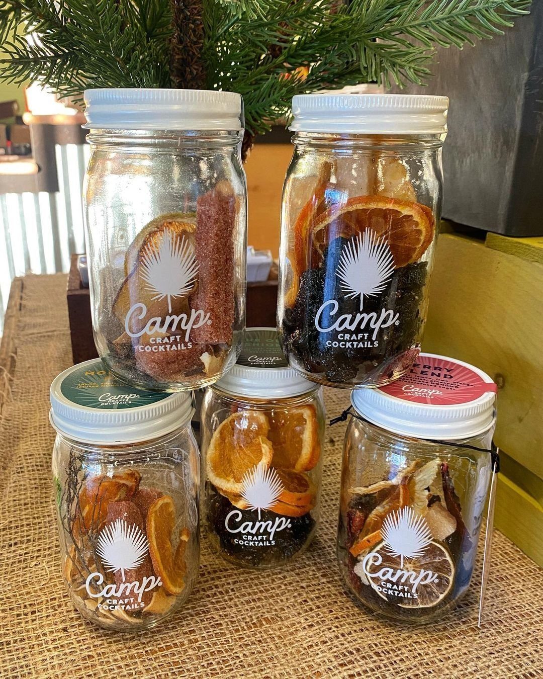 Glass mason jars filled with dried fruit and spices for cocktail infusion kits.