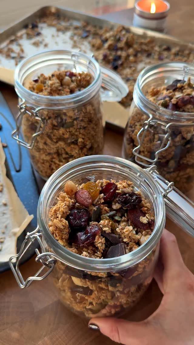 Homemade granola with dried fruit and chocolate in glass clamp-top jars.