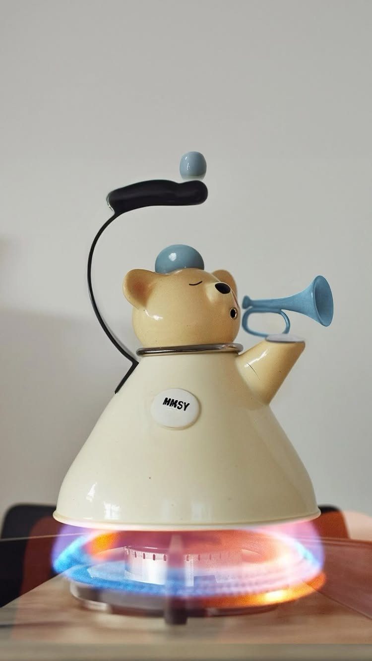 Bear-shaped cream tea kettle with a blue horn heating on a gas stove.