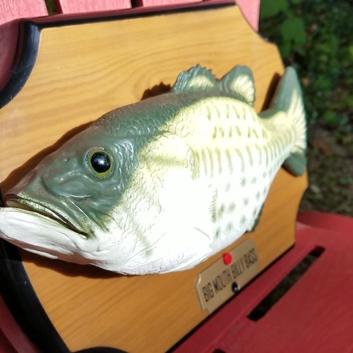 Big Mouth Billy Bass singing fish mounted on a wooden plaque on red chair