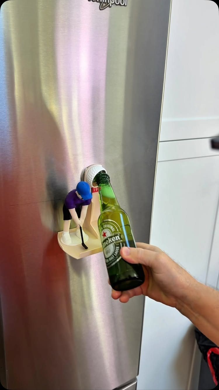 Hockey player figurine bottle opener mounted on a stainless steel refrigerator opening a beer