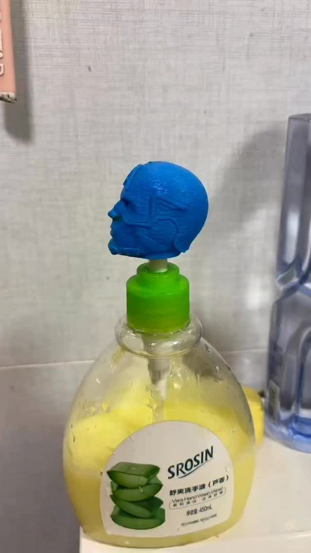 Soap dispenser bottle with a small blue sculpted man's head on the pump.