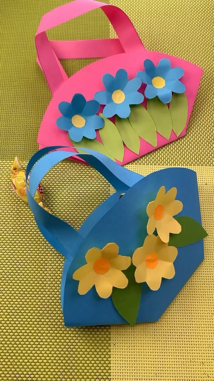Handmade pink and blue paper gift bags decorated with colorful paper flowers.