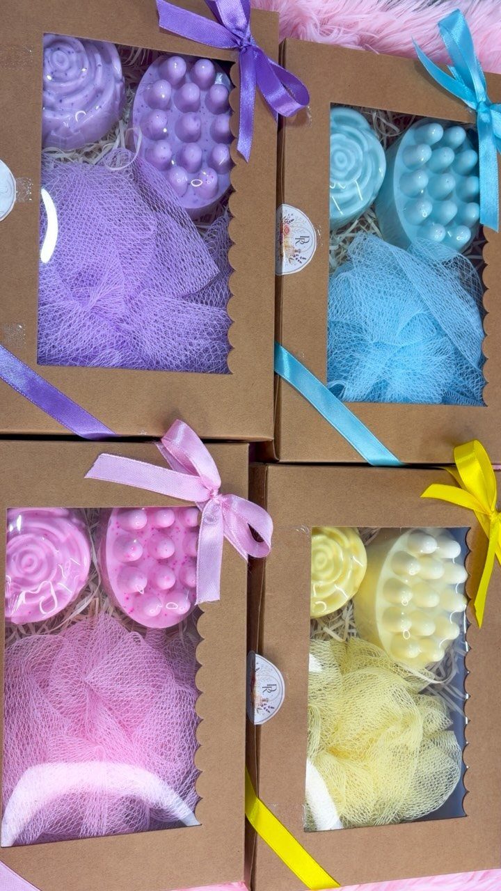 Four brown gift boxes containing colorful handmade soaps and matching bath sponges.