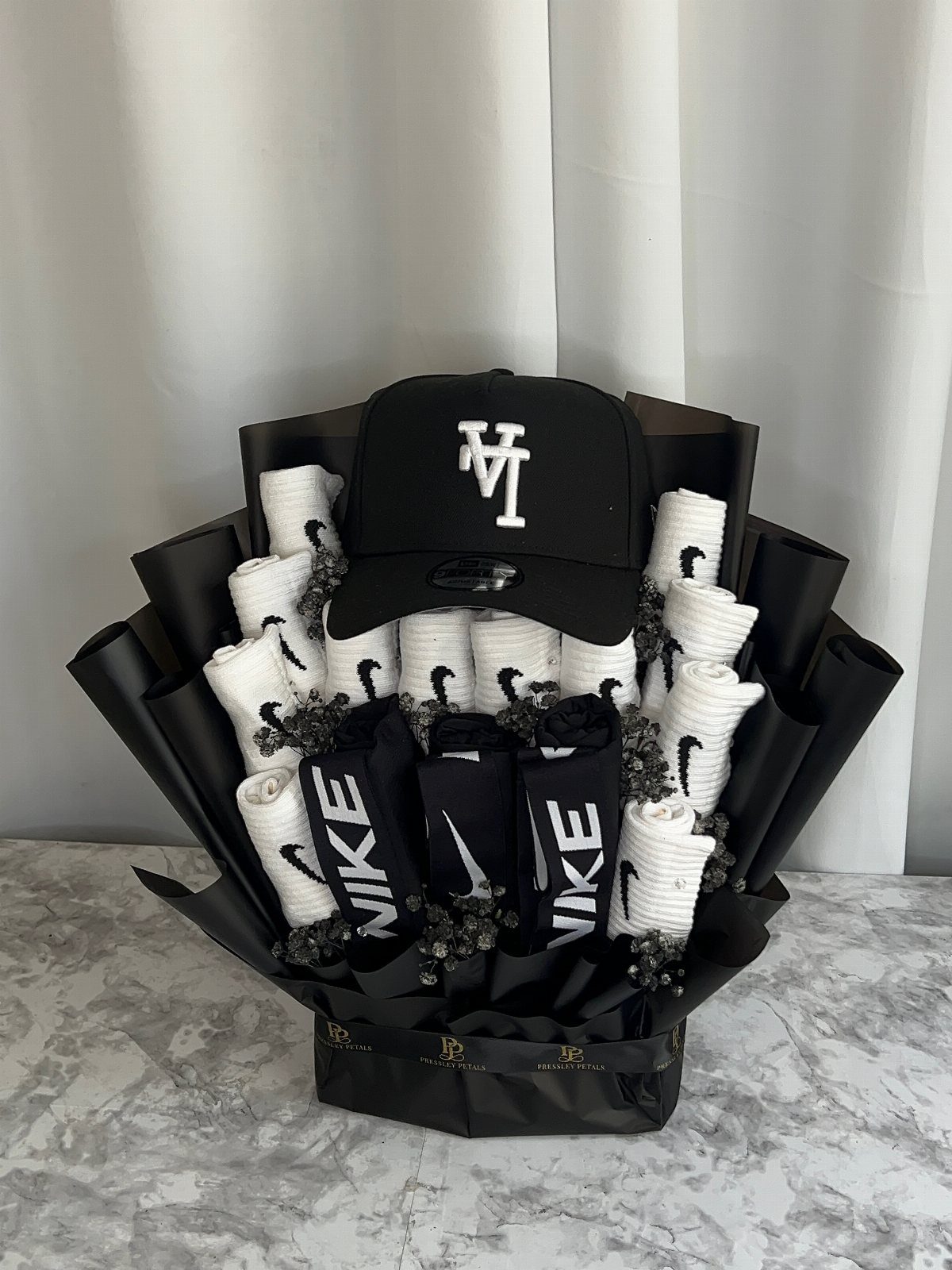 Nike socks and a black LA baseball cap arranged in a black gift wrap.