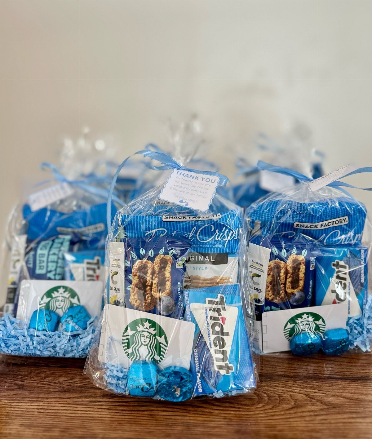 Clear gift bags filled with blue snacks, candies, and Starbucks gift cards.