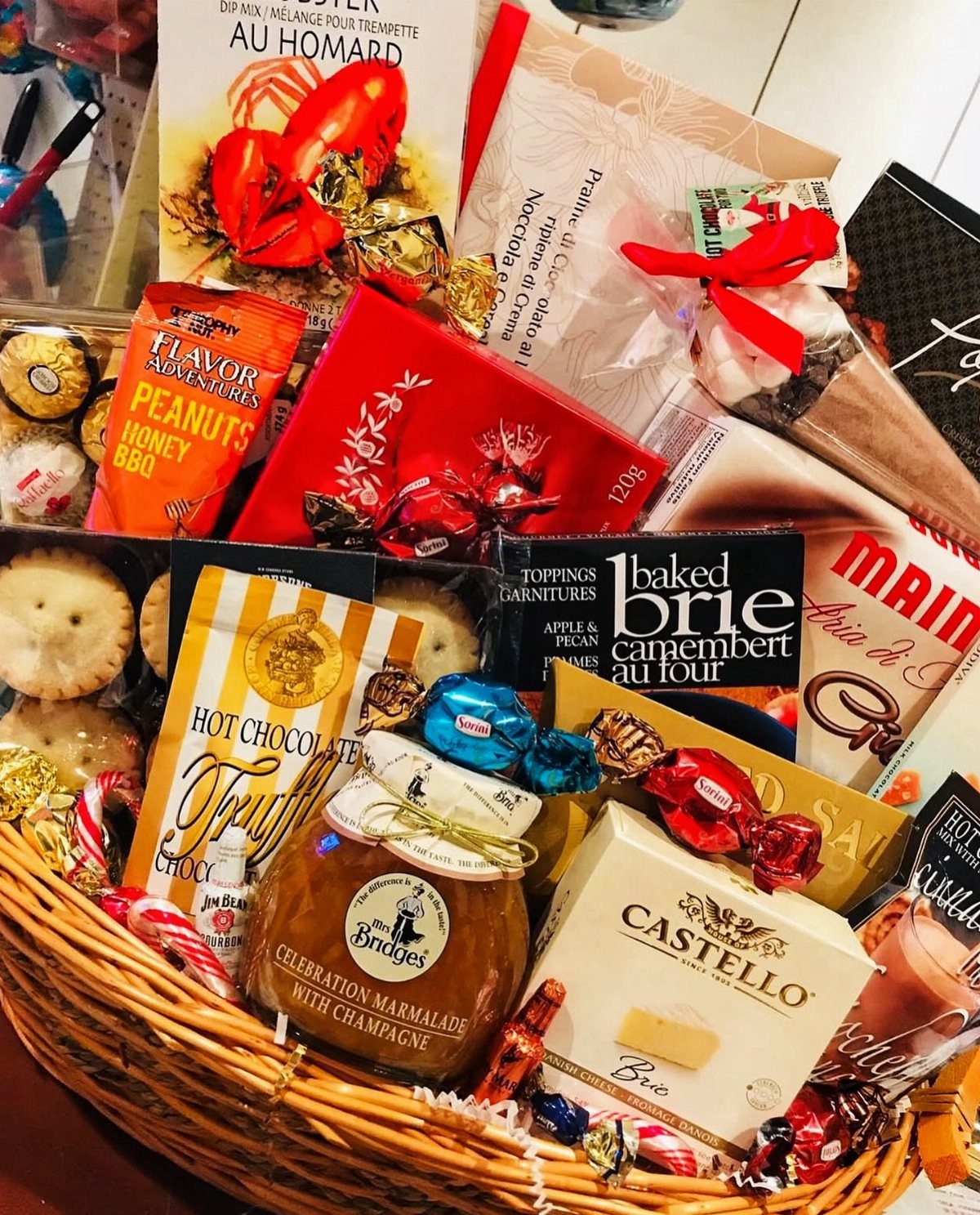 Gift Basket Ideas for Staff: 8 Picks From Wine to Coffee 2 Wicker gift basket filled with gourmet snacks, brie cheese, marmalade, and a cookbook.