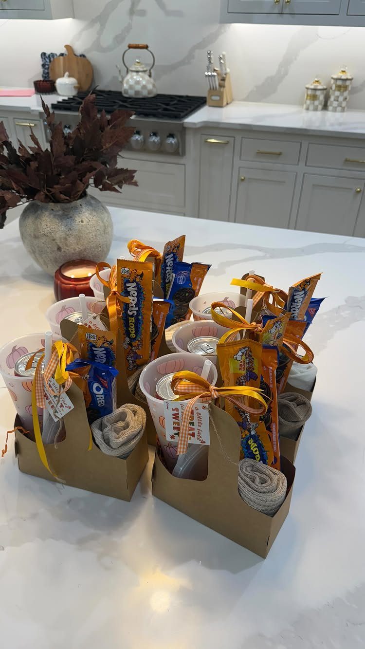 Small brown cardboard gift baskets filled with snacks and ribbons on a marble counter