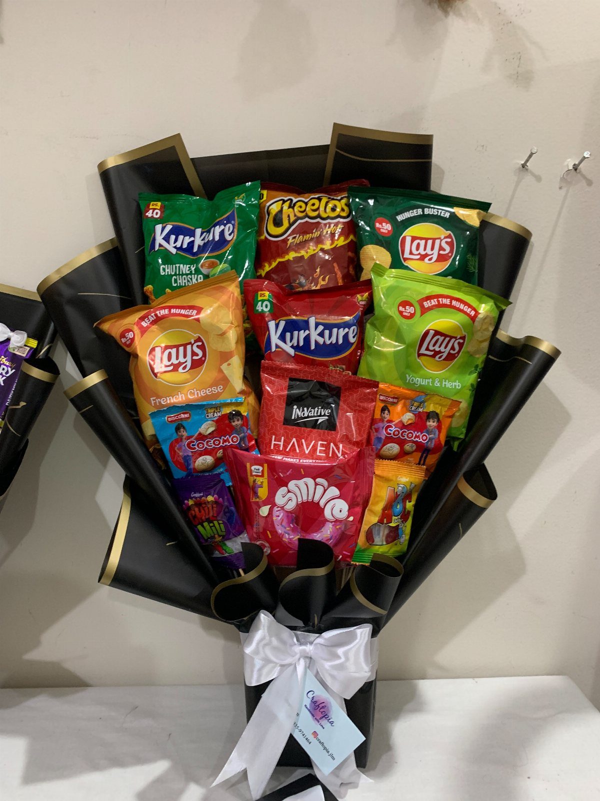 Snack bouquet with various chips and treats wrapped in black and gold paper.