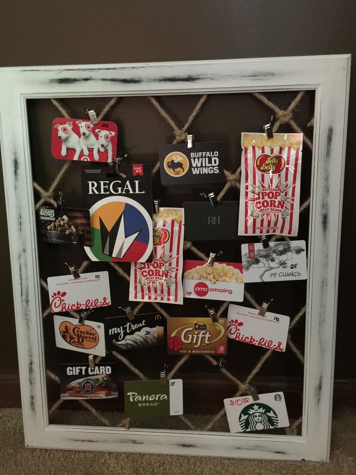 Gift cards clipped to a twine pinboard inside a white wooden frame