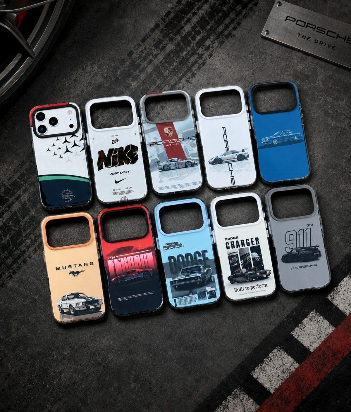 Ten smartphone cases with car and brand designs on a dark textured surface.
