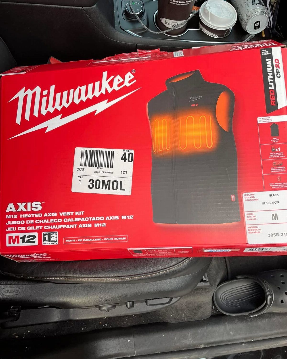 Milwaukee heated vest kit in a red box resting on a car seat