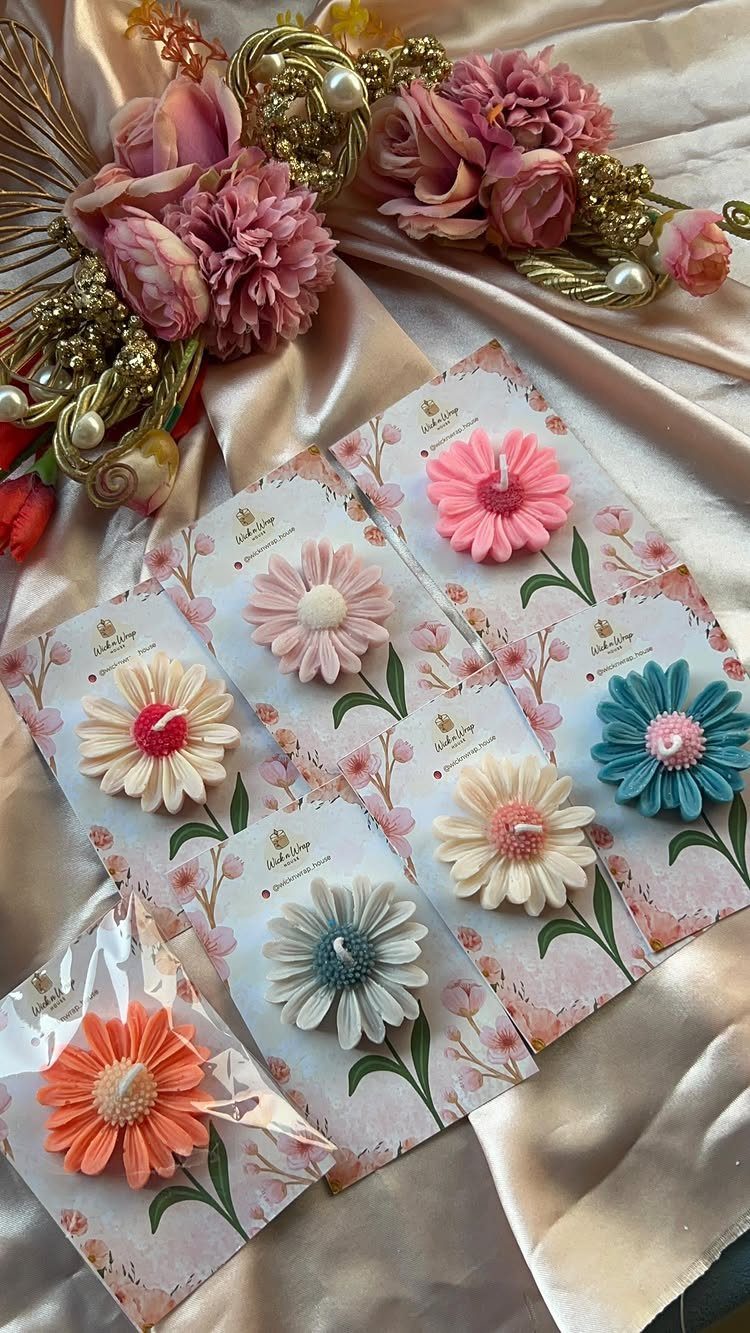 12 Gift Ideas for the Office Your Coworkers Will Use 12 Flower-shaped candles on floral cards arranged on satin fabric with pink blossoms.