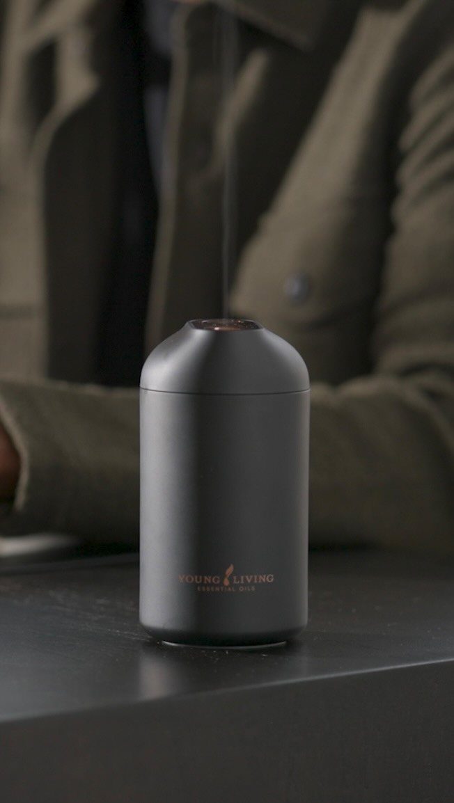 12 Gift Ideas for the Office Your Coworkers Will Use 10 Matte black essential oil diffuser on a desk with a blurred person behind.
