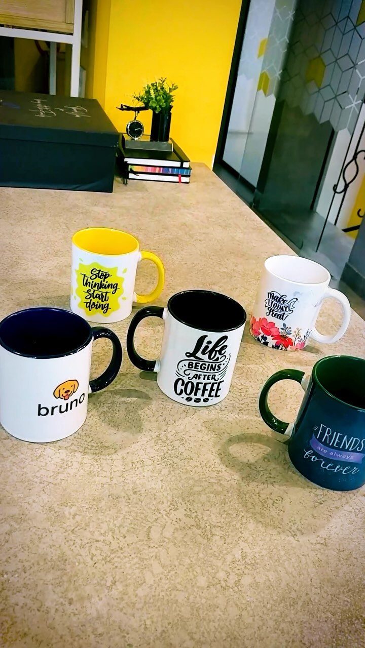 12 Gift Ideas for the Office Your Coworkers Will Use 2 Five ceramic mugs with printed quotes and names on a light-colored table.