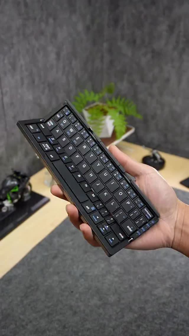 12 Gift Ideas for the Office Your Coworkers Will Use 8 Small black portable wireless keyboard held in a hand over an office desk