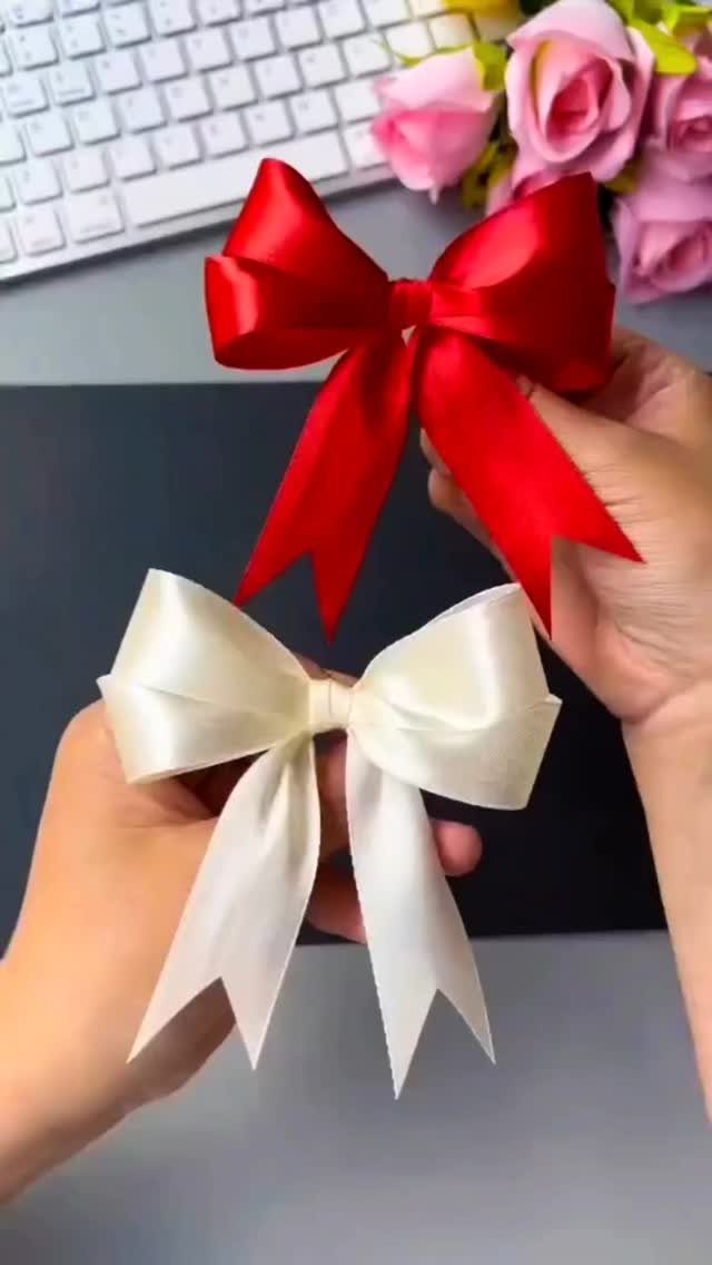 Red and white satin bows held by hands against a keyboard and roses.