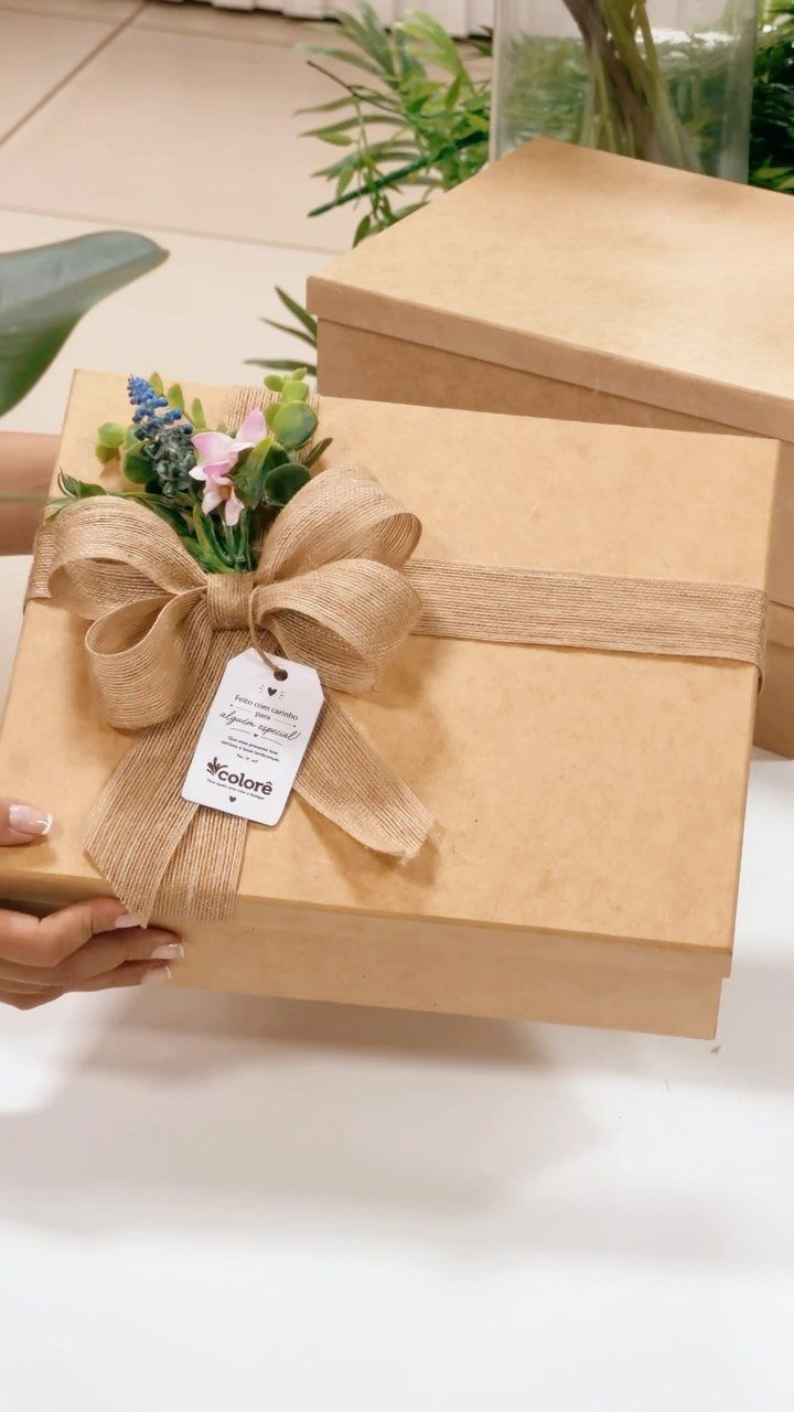 Brown kraft gift box tied with a rustic burlap ribbon bow and flowers