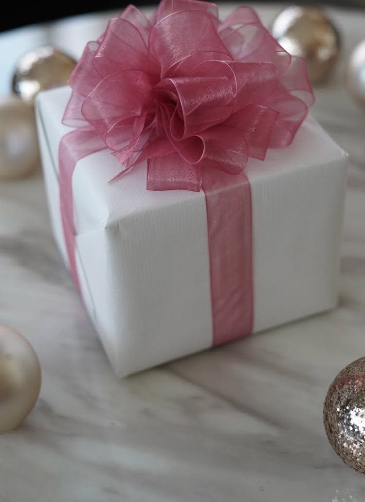 White gift box with pink satin ribbon and a large sheer organza bow.