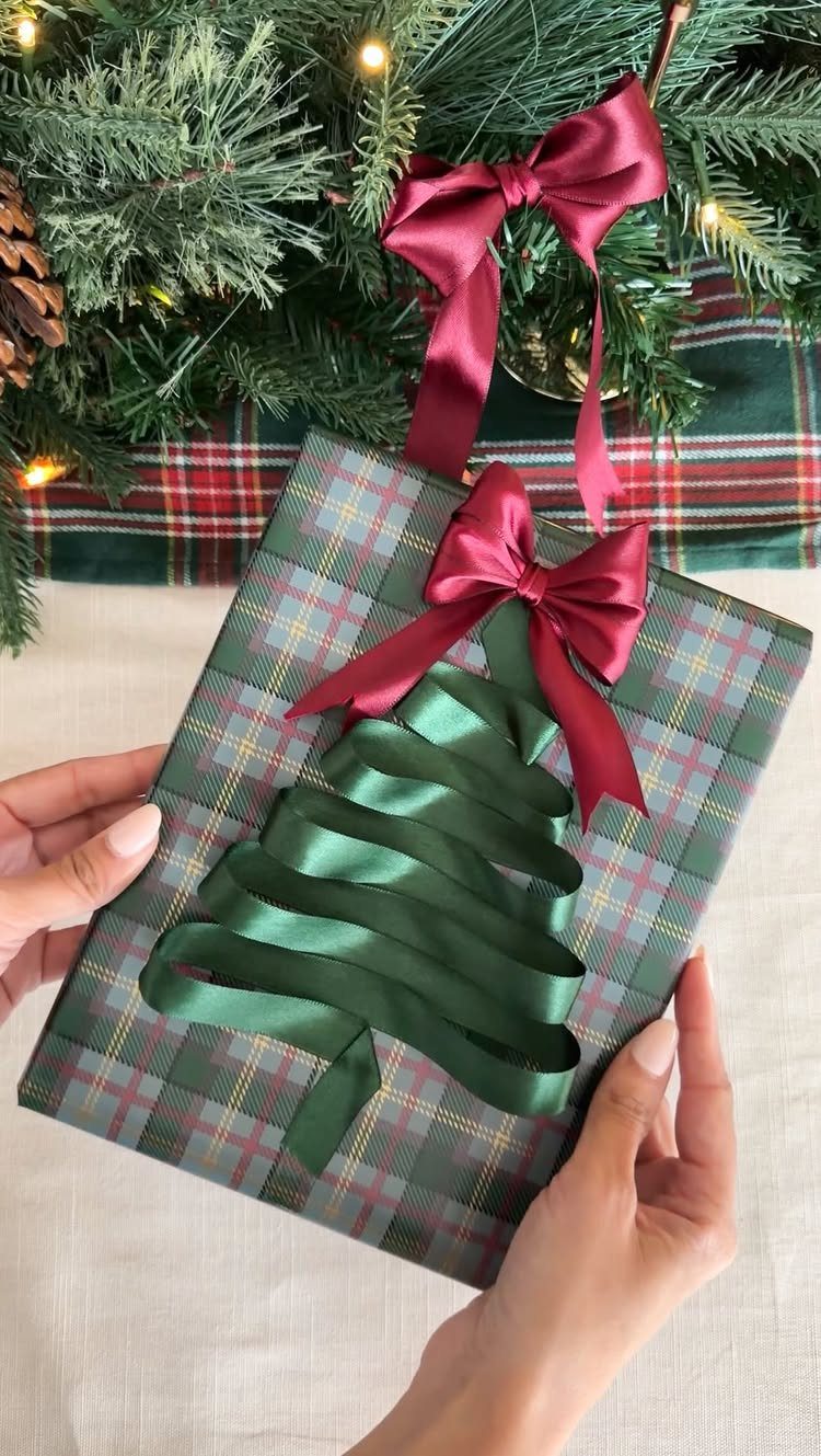 Plaid wrapped gift with a green ribbon Christmas tree and red bow.