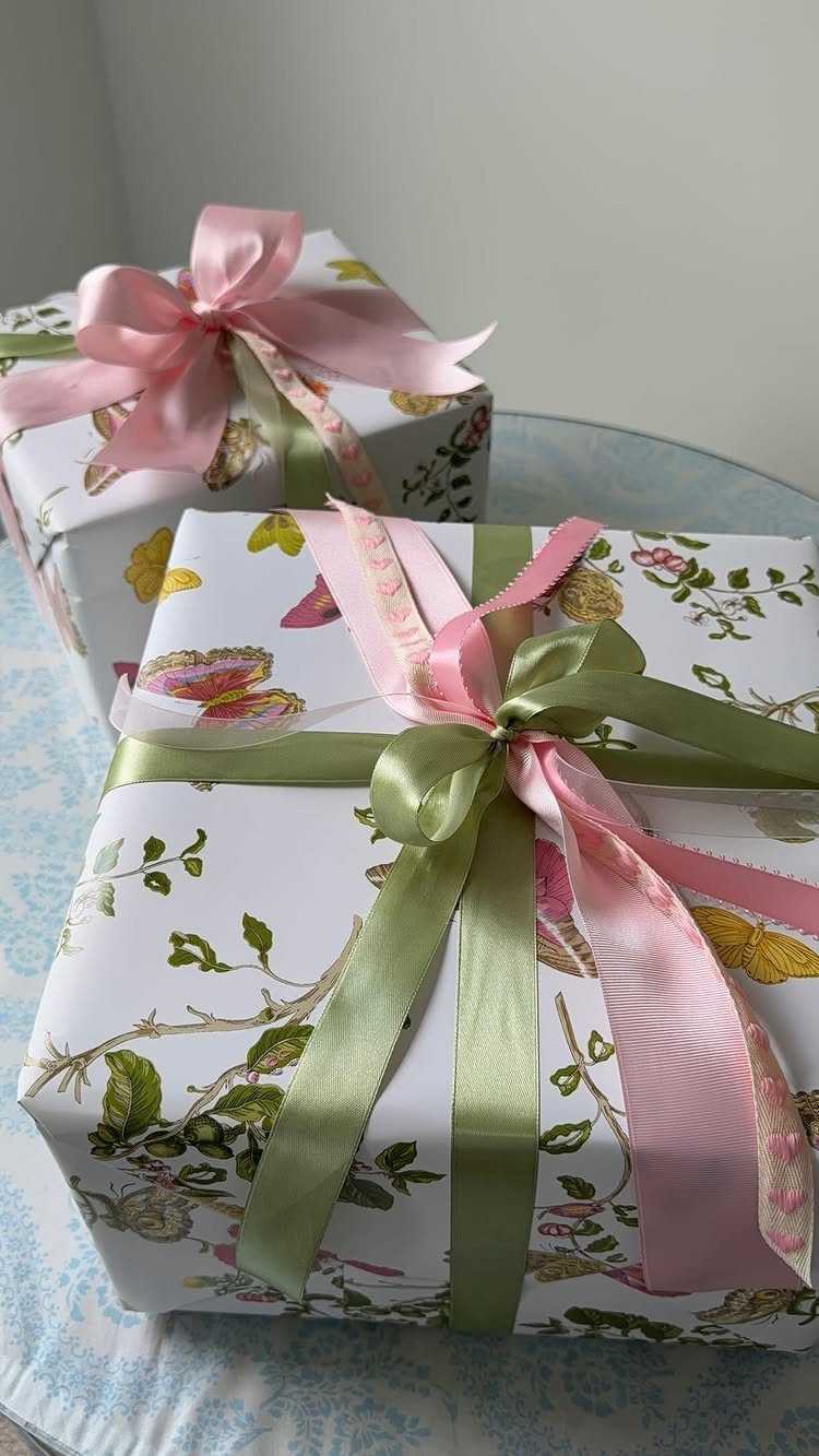 Floral wrapped gift boxes tied with shiny pink and green satin ribbons.