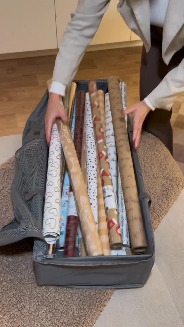Gift wrap rolls stored inside a grey fabric storage bag on a carpet.