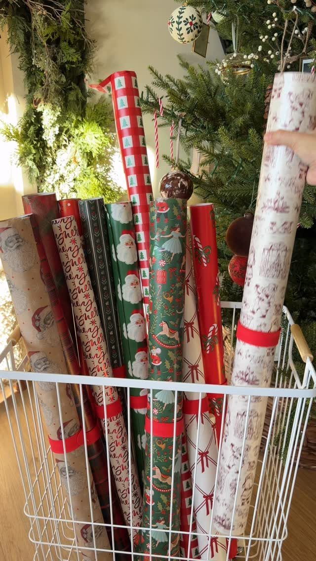 Christmas gift wrap rolls stored upright in a white wire laundry hamper basket
