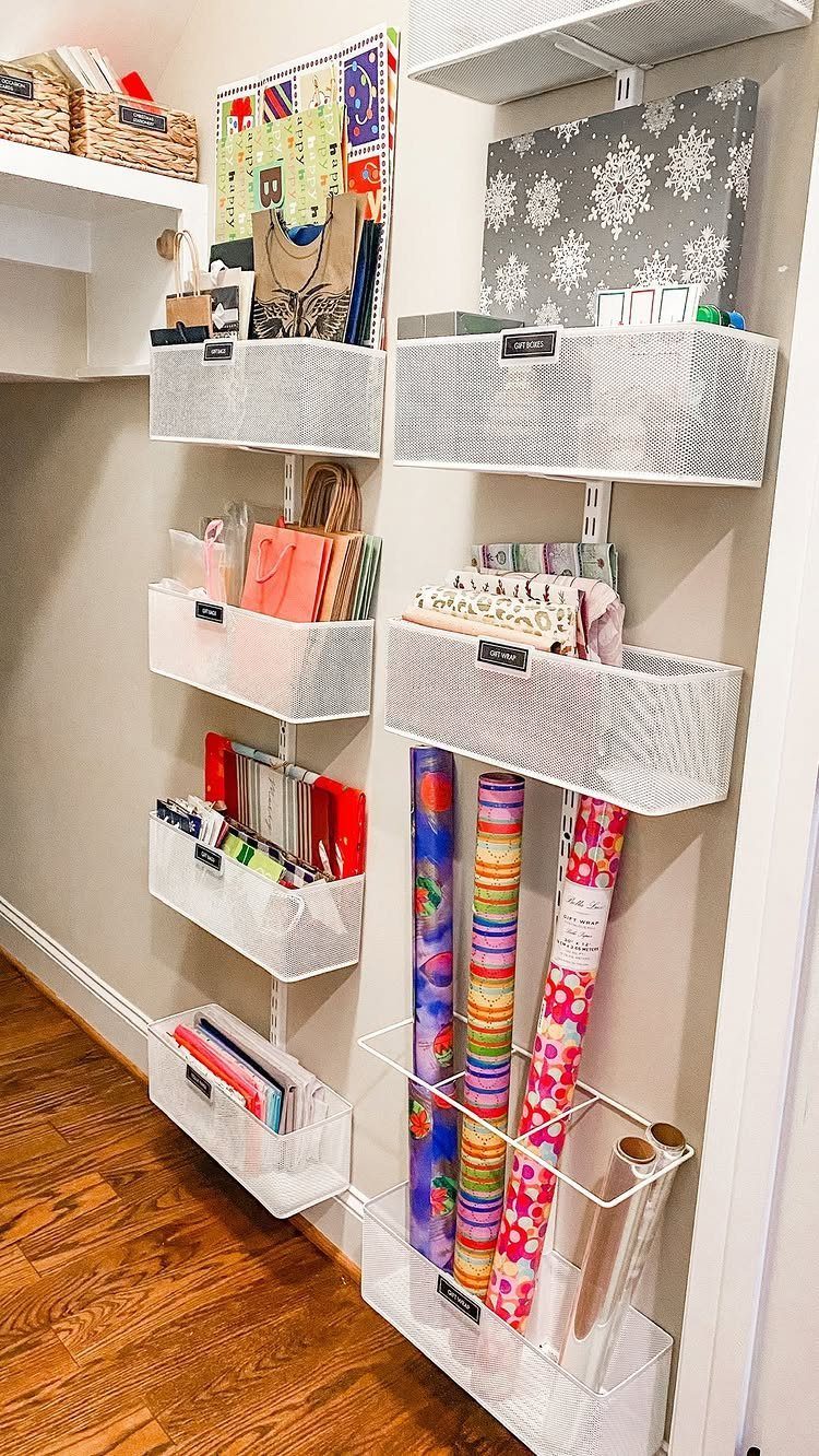 Wall-mounted white mesh bins and vertical holders organizing colorful gift wrap and ribbons.