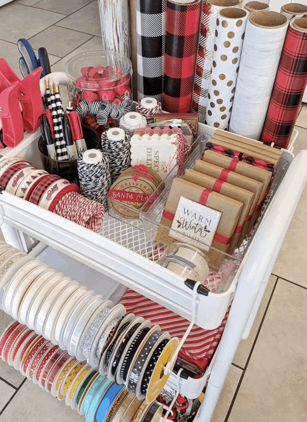 White rolling cart organized with wrapping paper rolls, ribbons, and twine supplies.